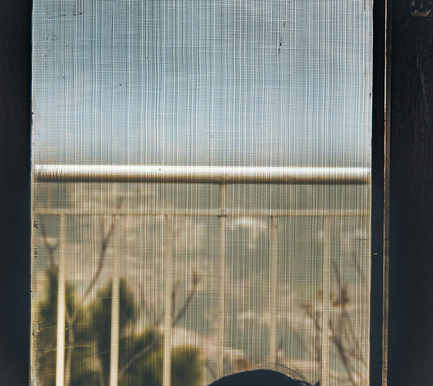 A minimalist view through a mesh screen showing railings outdoors.